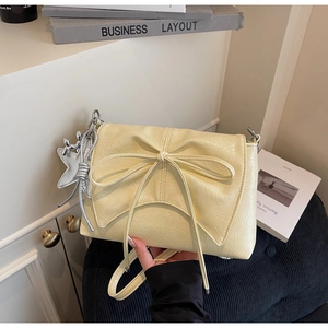 Détail du sac en cuir crème avec un grand nœud et un pendentif étoile argenté