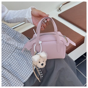 Détail du sac à main en cuir rose clair avec accessoire breloque ours en peluche