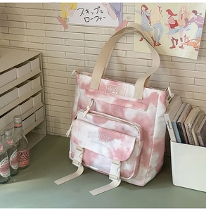 Detail showing pink tie-dye canvas backpack with buckle pocket and brand logo