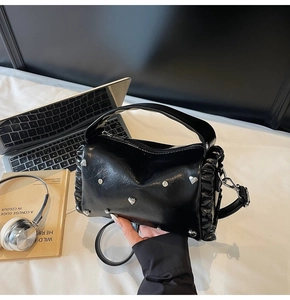 Detail of black PU tote bag with silver heart studs and butterfly hardware on desk
