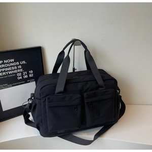 Detail of multi-pocket black travel bag with dual handles and adjustable strap