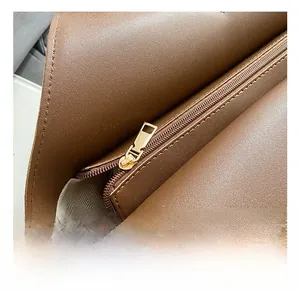 Detail of premium golden metal zipper and herringbone fabric lining on brown leather tote