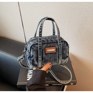 Detail of vintage blue denim pillow bag featuring leather patch and silver zipper