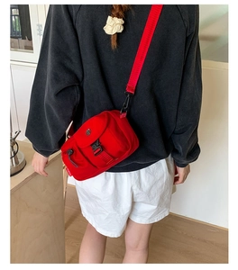Close-up of red nylon crossbody bag with flap buckle and Moborn brand tag detail