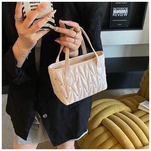Close-up of quilted cream handbag with rhinestone studs and elegant top handles