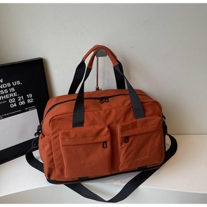 Detail view of brick orange travel bag with dual zipper pockets and black straps
