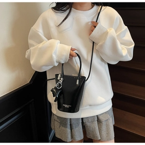 Detail of a black leather bucket bag with white fashion text and star charm accessory