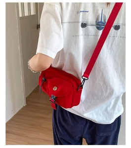 Detailed back view of a red nylon crossbody bag with buckle and adjustable strap