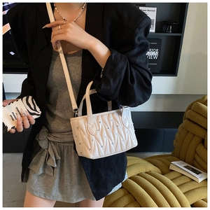 Detail showing white quilted mini bucket bag with crystal studs and leather strap