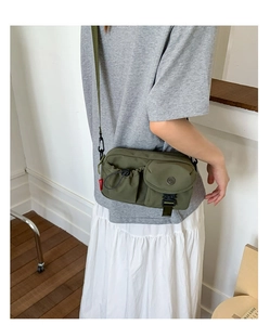 Detail of olive green nylon crossbody bag showing tactical pockets and buckle closure