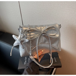 Détail d'un sac argenté avec nœud et breloque étoile de mer sur des livres d'art