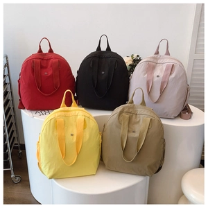 Waterproof nylon backpacks in five pastel colors arranged on white cylindrical displays