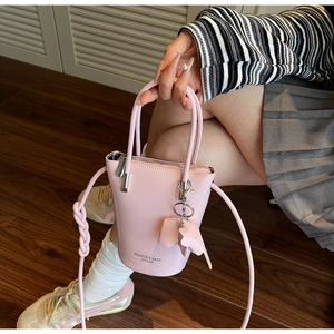 Pink PU leather bucket bag with elephant charm and shoulder strap shown on a model