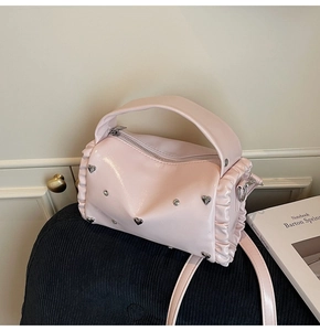 Detailed view of pink glossy tote bag with heart metal buckle and pleated trim design