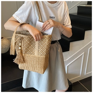Detail of bohemian straw tote bag with woven texture and long tassel wooden bead charm