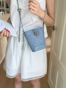Blue denim bucket bag with silver twist lock and chain strap shown on a model
