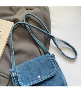 Close-up of denim crossbody bag showing fabric texture and silver metal button detail