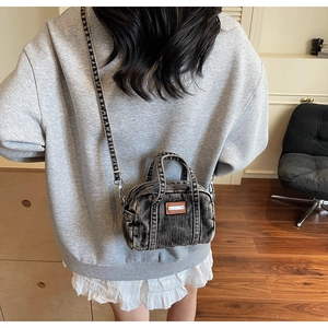 Detailed view of vintage washed black denim mini Boston bag with brown leather patch