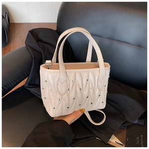 Detail of beige quilted bucket bag with shimmering rhinestones and leather cross-body strap
