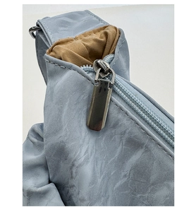 Detailed macro view of the silver metal zipper and marble-textured fabric on the blue handbag