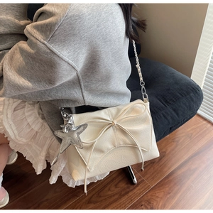 Détail du sac bandoulière crème avec un grand nœud et un pendentif étoile argenté