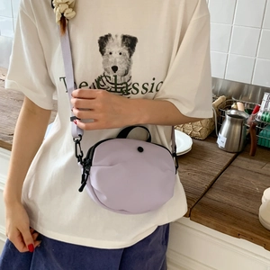 Close-up of minimalist lavender nylon mini crossbody bag with black zipper and strap