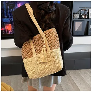 Detail of hollow woven straw tote bag featuring mesh texture and decorative tassel