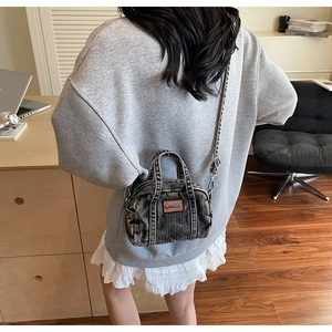 Detail of mini washed denim crossbody bag with brown leather patch and silver hardware