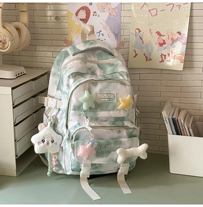 Detail of green tie-dye student backpack with cute plush pendants and multiple zip pockets