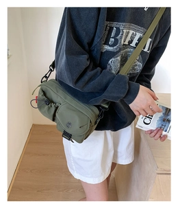 Close-up of army green crossbody bag with multiple pockets and black buckle details