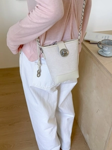 Creamy white tweed bucket bag with silver metal swivel lock and elegant chain strap