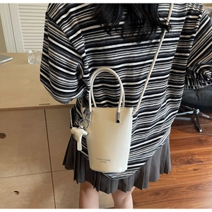 Close-up of beige bucket bag with elephant charm and Fashion & Bags text print