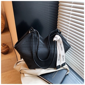 Détail du motif ajouré au laser sur le sac cabas noir avec ruban décoratif chic