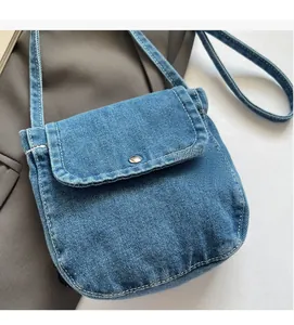 Close-up of blue denim messenger bag with white stitching and metal buckle detail