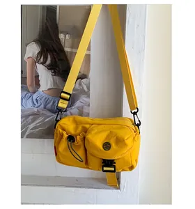 Detail of yellow nylon crossbody bag featuring multi-pocket structure and tactical buckle
