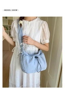 Detail of light blue pleated nylon shoulder bag with drawstring and heart pendant