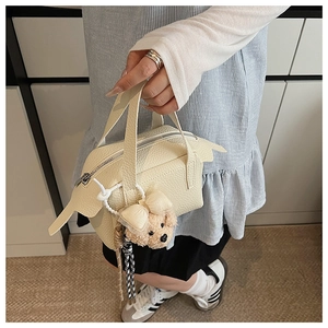 Détail du sac à main en cuir grainé crème avec accessoire de charme d'ours en peluche