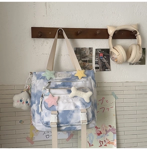 Detail of blue tie-dye canvas backpack with plush stars and a cloud charm on white wall