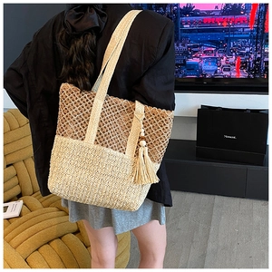 Detailed close-up of handmade hollow-out straw tote bag with tassels and shoulder strap