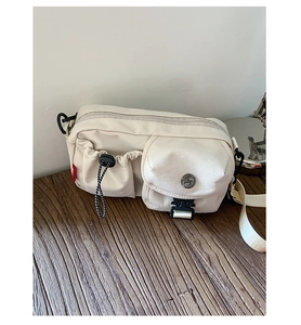 Detail view of cream canvas crossbody bag with drawstring side pocket and buckle closure