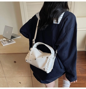 Detail of white PU leather tote with butterfly metal studs and ruffled side accents