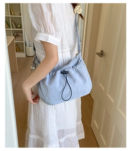 Close-up of light blue pleated dumpling bag with drawstring and silver heart charm