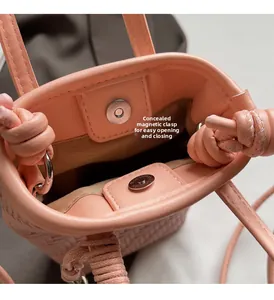 Détail du sac seau tressé rose avec fermoir magnétique invisible et poignée à nœuds décoratifs