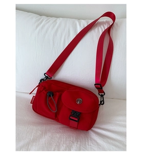 Detail view of red nylon crossbody bag featuring multi-pocket design and adjustable strap