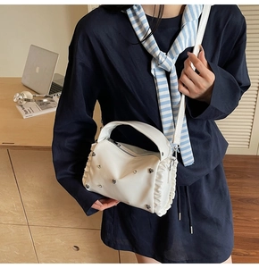 Detailed view of white PU leather tote bag with heart rivets and ruffled side edges