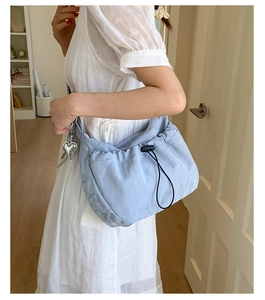 Detail of light blue ruched crossbody bag with heart pendant and drawstring closure