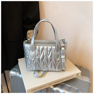 Detail of silver quilted bucket bag with rhinestones and metal finish on a book