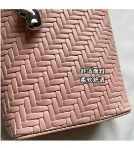 Gros plan sur un sac seau rose en cuir tressé avec une boucle en métal argenté en cœur