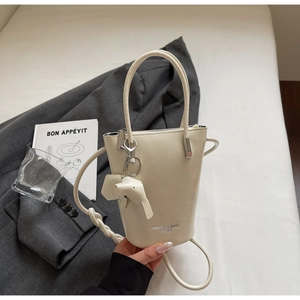Detail of cream leather bucket bag with cute elephant charm on a stylish blazer