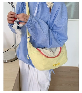 Close-up of apple shaped crossbody bag with embroidery and plush puppy charm